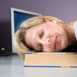 Woman asleep on book on desk